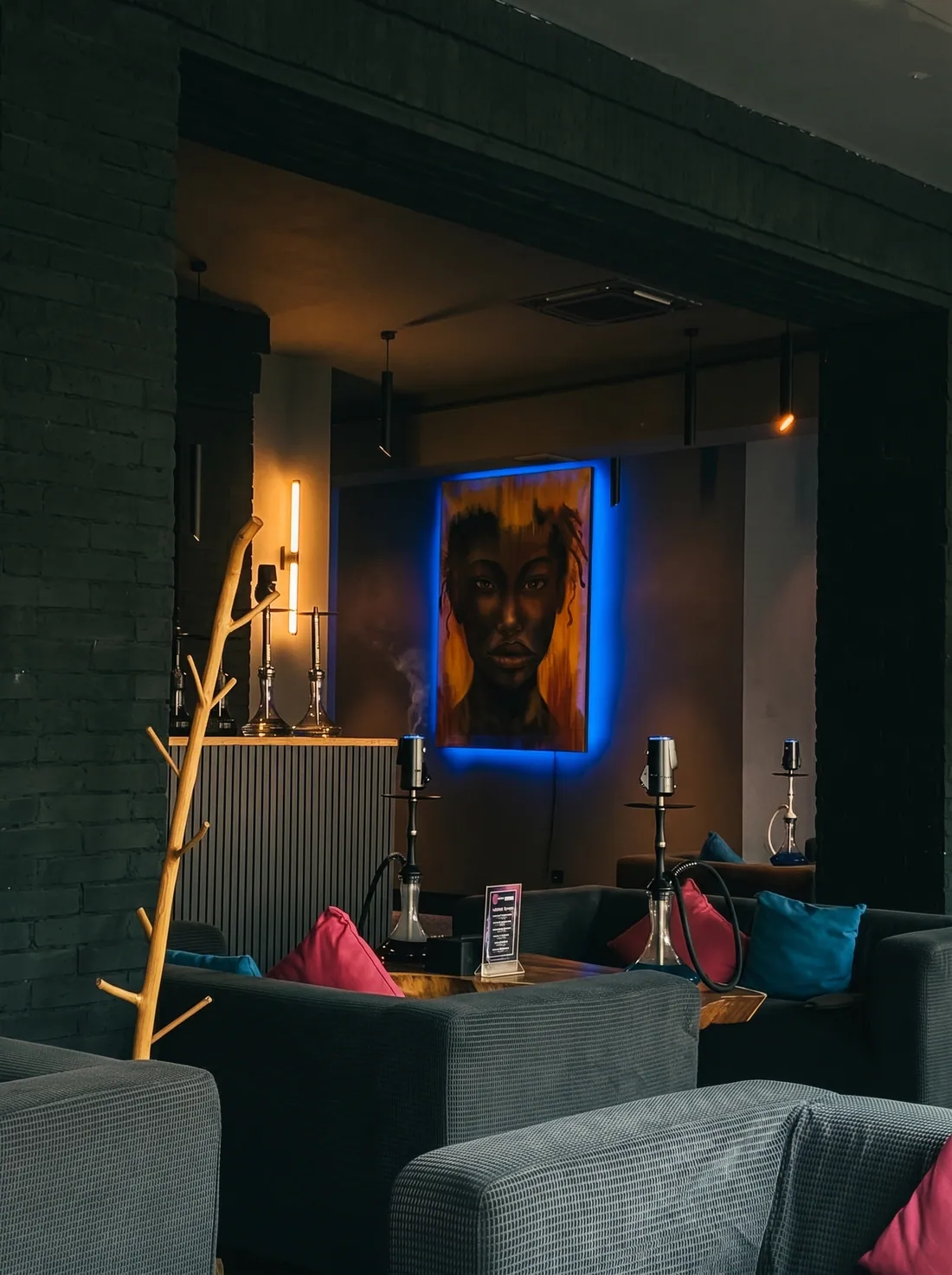 Brick arch opening onto a table with two hookahs under a portrait with blue backlight