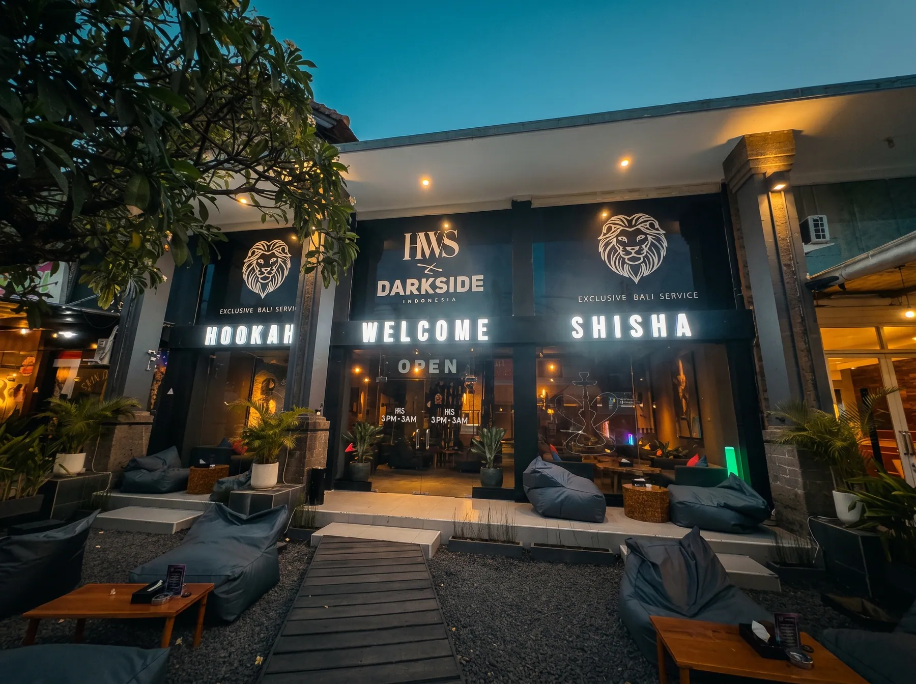 HWS x Darkside facade at blue hour with glowing HOOKAH, WELCOME and SHISHA signs and bean bags on the terrace
